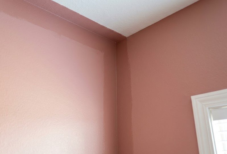 A darker frame of brushed paint along the ceiling line and corner of a pink wall