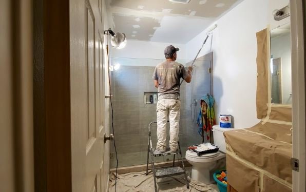 painter priming the patched ceiling