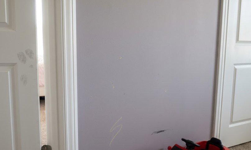 Scuffed hallway wall with handprints and pen marks that won't wash off